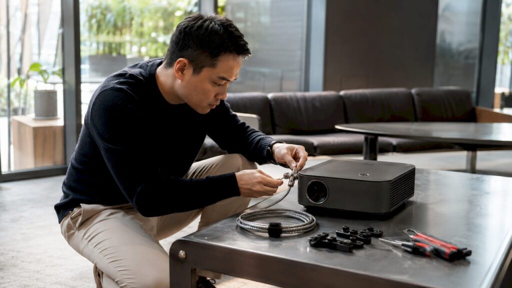 Technician securing projector with cable lock on desk