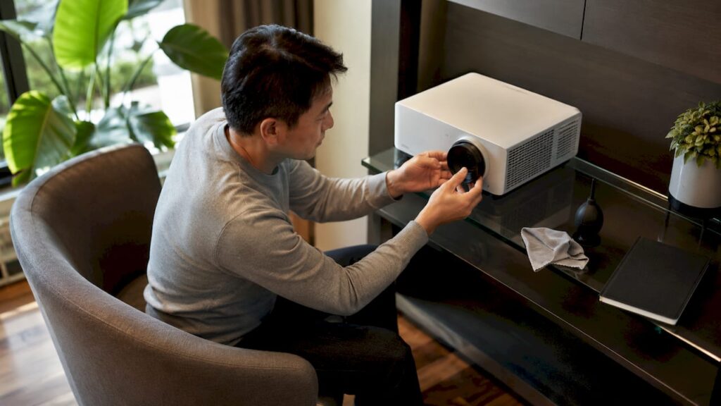 Man cleaning projector lens at home