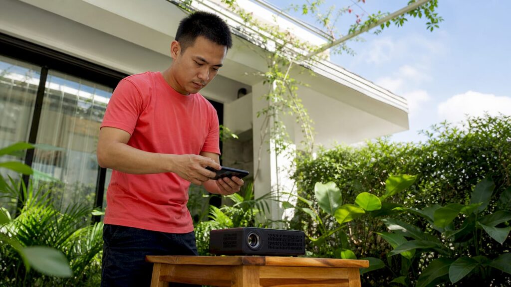 Seorang lelaki menikmati menonton filem di rumah dengan menggunakan projektor tanpa wayar.