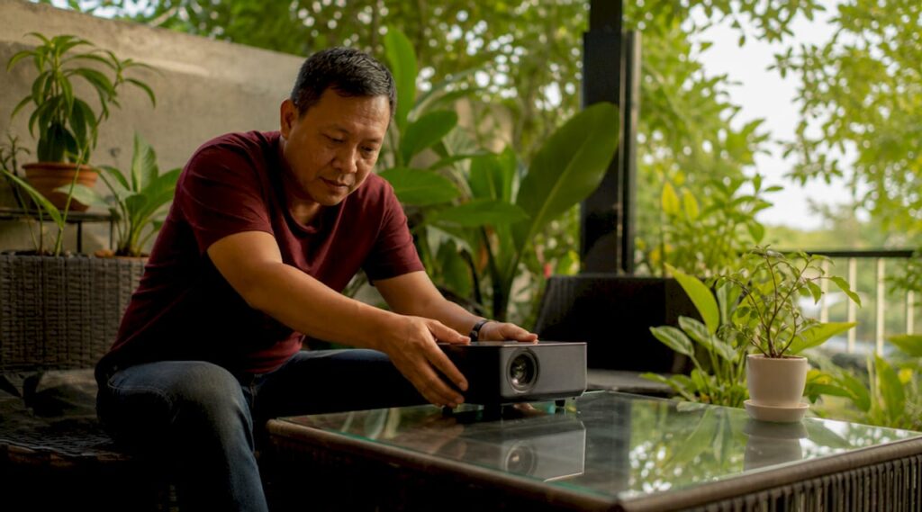 Man setting up mini projector in living room