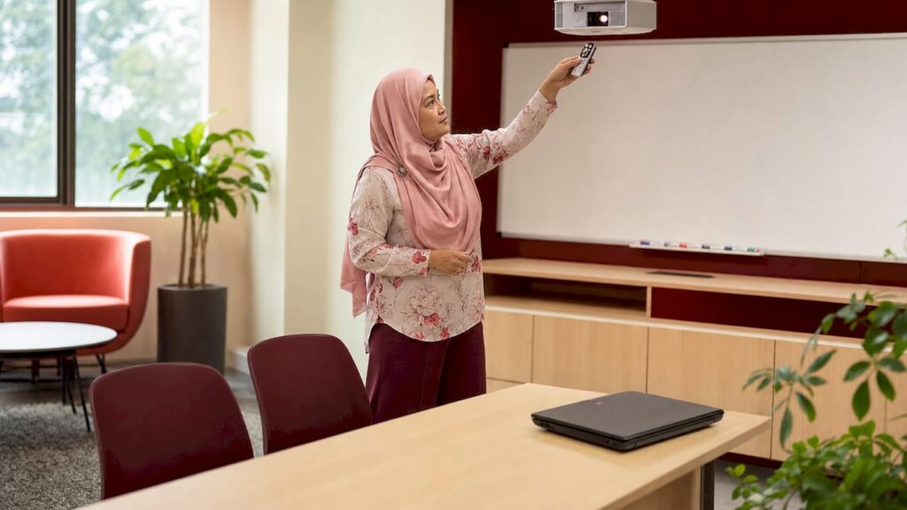 Office manager adjusting wireless projector in staff room